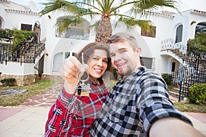 Moving and real estate concept - Happy young laughing cheerful couple man and woman holding their new home keys in front
