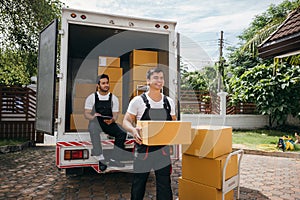 Moving service workers unload boxes from a van showing teamwork and cooperation