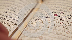 A moving shot in a half circle showing a person reading a Quran