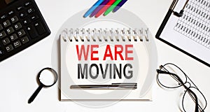WE ARE MOVING text in the office notebook with office tools, business concept