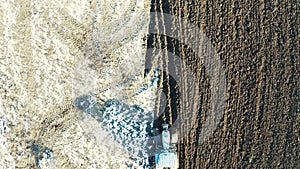 A moving tractor, plowing field in winter