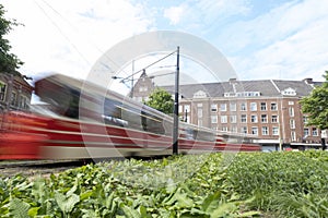 A moving tram at day, houses in background, blue sky, in long exposure. The Hague, the Netherlands