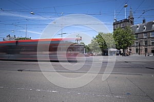 A moving tram at day, houses in background, blue sky, in long exposure. The Hague, the Netherlands