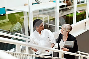 Moving up and straight towards success. two businesspeople walking up a staircase together in an office.