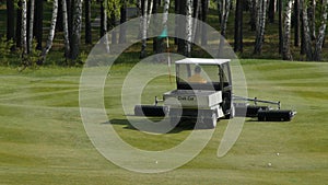 Mower work in the grass at the edge of a Scottish golf course. Machine for turf on Golf