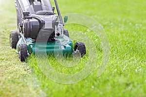 Mowing or cutting the long grass with a green lawn mower