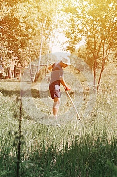 mowing the grass traditional old-fashioned way with the hand scythe on the household village farm