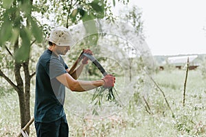 mowing grass traditional old-fashioned way with hand scythe on household village farm. young mature farmer man