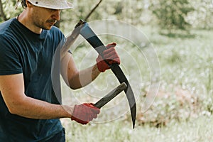 mowing grass traditional old-fashioned way with hand scythe on household village farm. young mature farmer