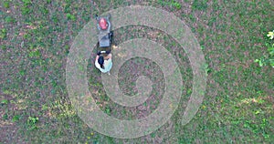 Mowing green grass in the backyard with a lawn mower near the house