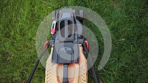 Mowing high green grass with corded electric lawn mower