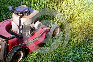 Mowing a lawn with a old style petrol gasoline lawnmower. Red lawn mower cutting grass . Gardening concept background