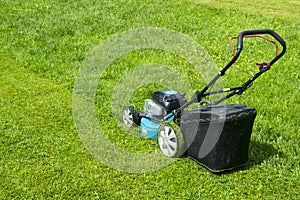 Mowing lawns. Lawn mower on green grass. mower grass equipment. mowing gardener care work tool close up view sunny day.