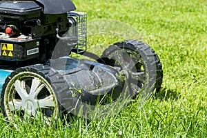 Mowing lawns. Lawn mower on green grass. mower grass equipment. mowing gardener care work tool close up view sunny day.