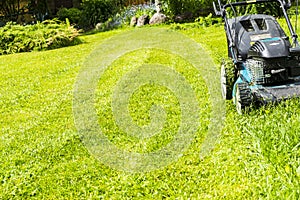 Mowing lawns, Lawn mower on green grass, mower grass equipment, mowing gardener care work tool, close up view, sunny day.