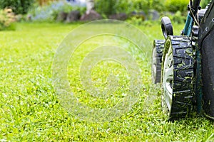 Mowing lawns, Lawn mower on green grass, mower grass equipment, mowing gardener care work tool, close up view, sunny day.