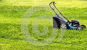 Mowing lawns. Lawn mower on green grass. mower grass equipment. mowing gardener care work tool. close up view. sunny day.