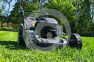 Mowing lawns. Lawn mower on green grass. Mower grass equipment. Mowing gardener care work tool. Close up view. Sunny day. Soft