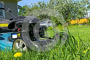 Mowing lawns. Lawn mower on green grass. Mower grass equipment. Mowing gardener care work tool. Close up view. Sunny day. Soft