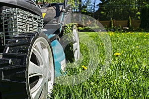 Mowing lawns, Lawn mower on green grass, mower grass equipment, mowing gardener care work tool, close up view, sunny day. Soft lig