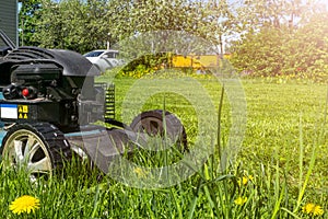 Mowing lawns. Lawn mower on green grass. Mower grass equipment. Mowing gardener care work tool. Close up view. Sunny day. Soft lig