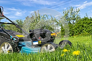 Mowing lawns. Lawn mower on green grass. Mower grass equipment. Mowing gardener care work tool. Close up view. Sunny day. Soft lig