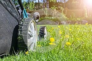 Mowing lawns. Lawn mower on green grass. Mower grass equipment. Mowing gardener care work tool. Close up view. Sunny day. Soft lig