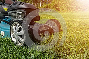 Mowing lawns, Lawn mower on green grass, mower grass equipment, mowing gardener care work tool, close up view, sunny day. Soft lig