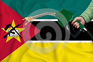 MOZAMBIQUE flag Close-up shot on waving background texture with Fuel pump nozzle in hand. The concept of design solutions. 3d