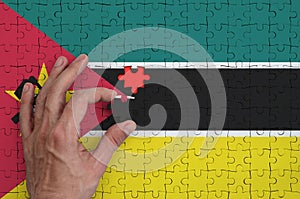 Mozambique flag is depicted on a puzzle, which the man`s hand completes to fold