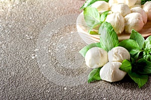 Mozarella small balls with fresh basil leaves on rustic background