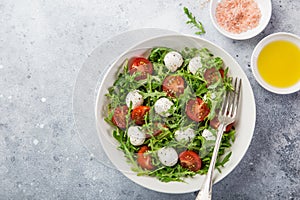 Mozarella, tomato and arugula salad in whute bowl