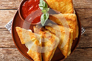 Mozzarella in carrozza is an Italian cheese sandwich made by breading and frying mozzarella-stuffed bread closeup on the table. photo