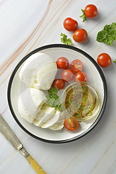 Mozzarella cheese and cherry tomatoes with spices. Homemade mozzarella cheese