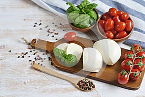 Mozzarella cheese with red tomatoes and basil leaves, pepper, olive oil