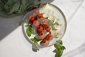 Mozzarella cheese, tomato, basil on a light background