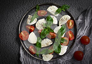 Mozzarella cheese, tomato, basil   nutrition  salad  a dark background