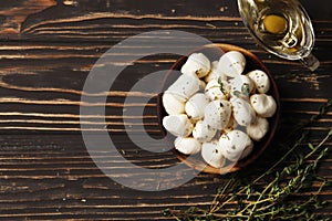 Mozzarella cheese in a wooden bowl with spices and butter on a wooden table