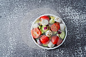 Mozzarella cucumber tomato red onion salad in a white bowl