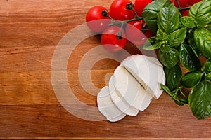 Mozzarella tomatoes and basil on a wooden rustic background