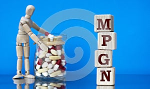 MPGN word on a wooden block on a blue background with pills and a wooden man