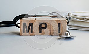 MPI inscription on wooden cubes isolated on white background, medicine concept. A stethoscope and protective masks are on the