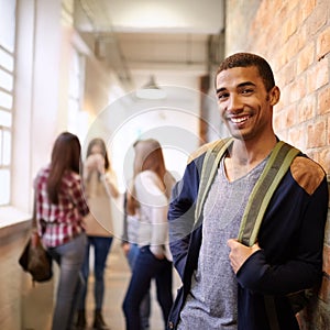 Mr Cool on campus. Portrait of a handsome young male student leaning against a wall with his friends in the background.