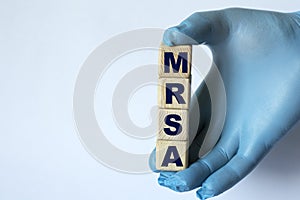 MRSA is an acronym on cubes held by a hand in a blue glove photo