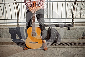 Msician is standing with his guitar outdoors