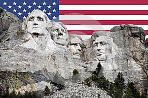 Mt. Rushmore National Memorial Park in South Dakota with American flag in background. Sculptures of former U.S. presidents; George