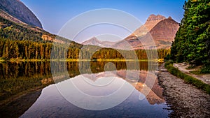 Mt. Wilbur reflection in the smooth surface of Fishercap Lake at sunrise in Glacier National Park photo