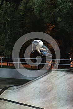 MTB bicycle rider does various tricks while riding in skatepark . Extreme Sports, rider does tabletop trick at night