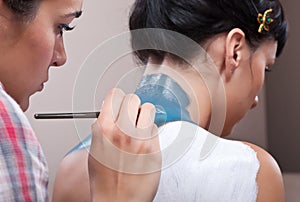 MUA painting background layers on girl's back photo