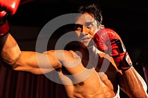 Muay Thai boxer punch his fist in front of camera posing. Impetus